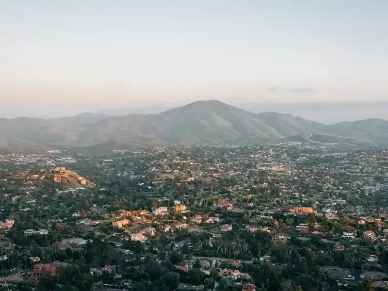 A sprawling suburban area with houses and trees at the base of a large mountain range. water damage restoration La Mesa