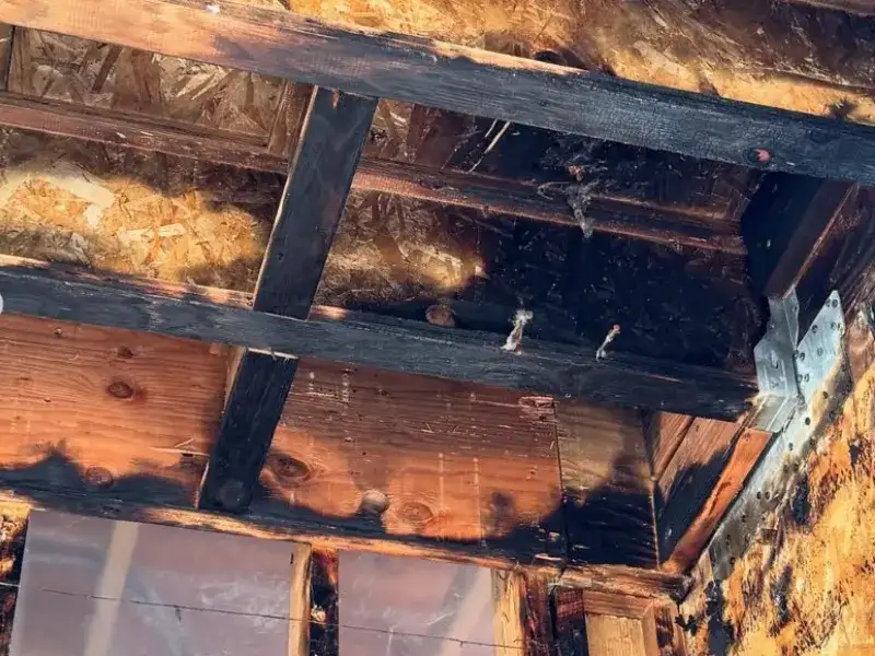 Charred wooden beams and ceiling joists showing fire damage inside a building. fire damage restoration